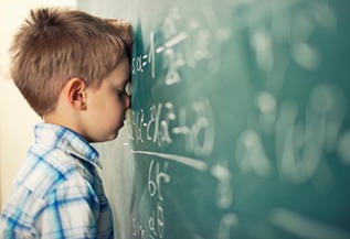 Child confused by math equations written on a classroom blackboard