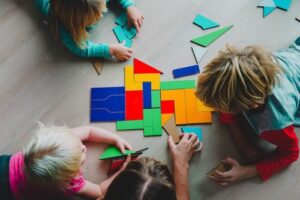 Children solving geometric math puzzles together on the floor