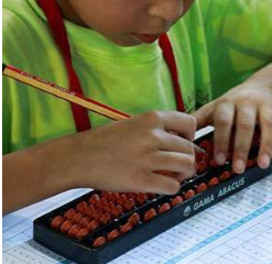 Close-up of a child's hands using a Gama abacus with a pencil during practice.