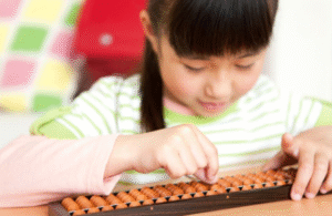 Young girl practicing calculations on an abacus to improve concentration and mental maths skills.