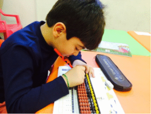 Young boy practicing abacus calculations to improve focus and mental maths skills.